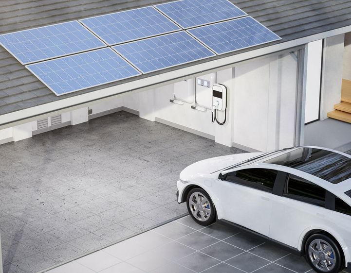 Garage eines Hauses mit Solarpanelen darauf und ein Elektro Auto das in die Garage inklusive Wallbox fährt